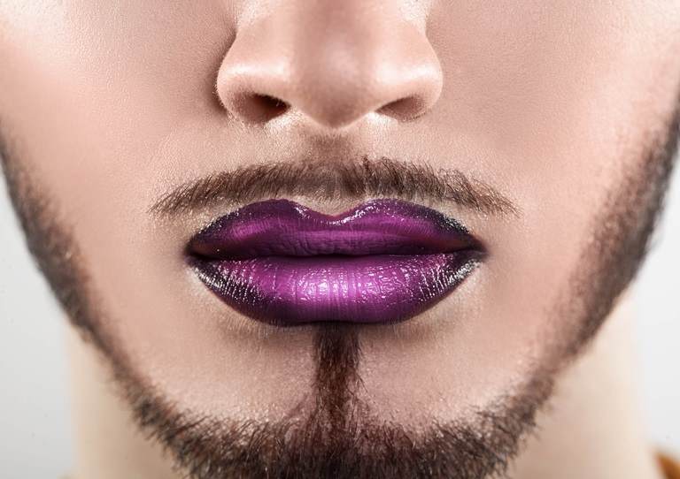 Genderless Beauty by Croda lower half of  a mans face with a well groomed beard wearing an ombre purple and black lipstick